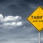 Tariff Bomb Over Smoke Yellow sign saying tariffs just ahead cloudy sky