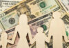 Wooden figures representing a family on a background of US dollar bills