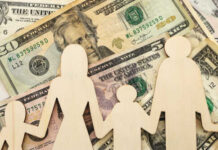 Default Tsunami Slams Millions Wooden figures representing a family on a background of US dollar bills