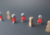 AI Ax Slams 9,000 Jobs Wooden figures representing people with red crosses indicating exclusion