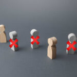 AI Ax Slams 9,000 Jobs Wooden figures representing people with red crosses indicating exclusion
