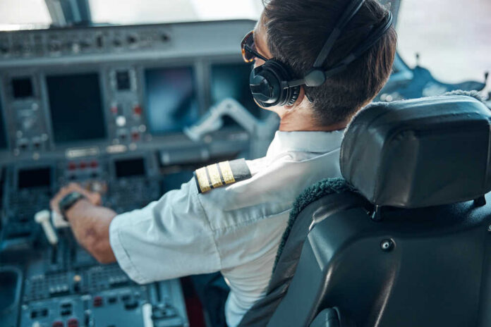 Top,View,Of,Man,In,Aviation,Uniform,And,Earphones,Sitting Pilot in cockpit wearing headphones and operating aircraft controls