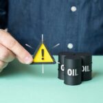 A person holding a warning sign next to oil barrels