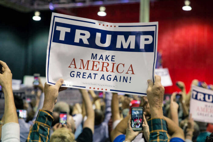 Large crowd holding Trump Make America Great Again sign.
