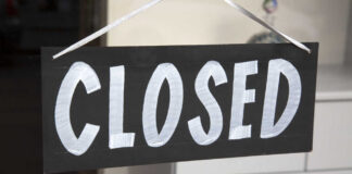A black sign with the word 'CLOSED' painted in white letters