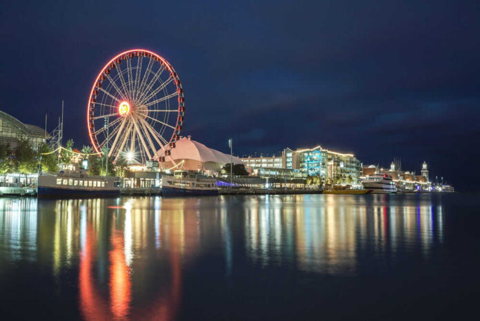 Ferris wheel and waterfront lights reflecting on water.