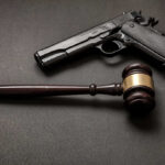 Pistol and judge's gavel on dark surface