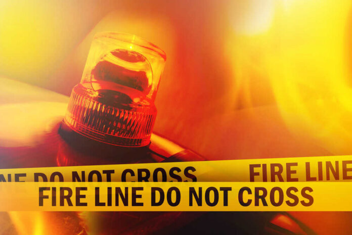 Fire,Line,Do,Not,Cross,Yellow,Headband,Tape,And,Orange Firefighter spraying water on a raging forest fire at night