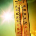 Hottest Month Ever Hits America Thermometer displaying high temperature against a bright sun