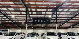 White Tesla cars displayed in showroom with Tesla sign.