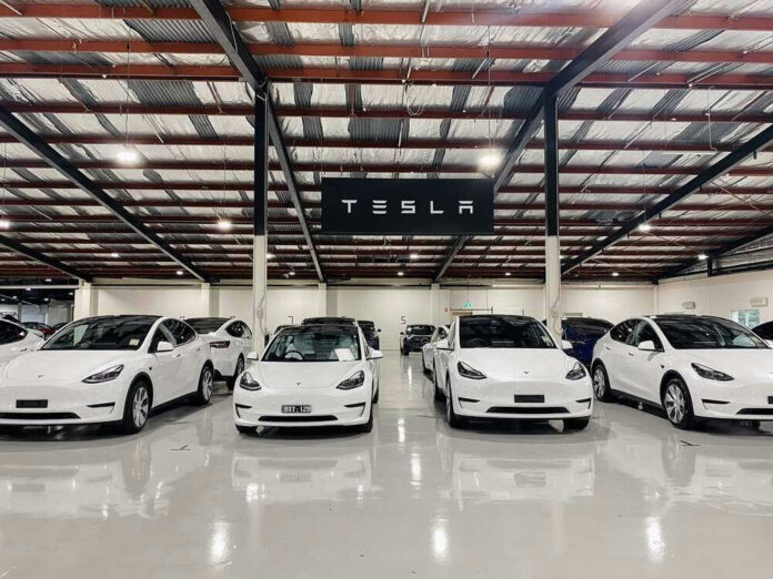 shutterstock_2190200775 White Tesla cars displayed in showroom with Tesla sign.