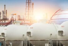Trump Targets Big Oil Windfall Gas storage tanks in an industrial facility during sunrise