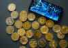 Bitcoin Vaults Cracked — Millions Vanish Various cryptocurrency coins scattered around a smartphone displaying market data