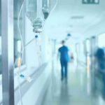 Hospital corridor with IV drip and healthcare worker.