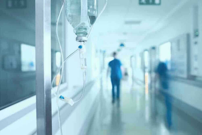 shutterstock_528854752-1 Hospital corridor with IV drip and healthcare worker.