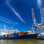 Trump Renames A Great Lake. Canada Fires Back Cargo ship docked at port with cranes unloading.