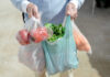 Food Recall Whiplash Hits Election Season Person carrying grocery bags with vegetables and fruits.