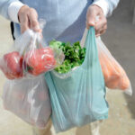 Food Recall Whiplash Hits Election Season Person carrying grocery bags with vegetables and fruits.