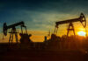Oil pumpjacks silhouetted at sunset on a rural field