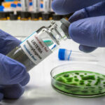 Taco Bell Lettuce Nightmare Explodes A laboratory technician holding a vial labeled 'Listeria monocytogenes' above a petri dish with green culture