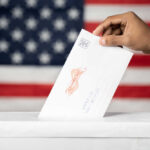 Hand inserting mail-in ballot envelope into ballot box