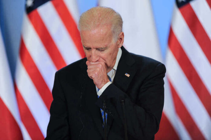 Joe Biden stands at a podium with U.S. flags in the background