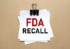 Stone-Laced Dessert? FDA Sounds Recall Alarm A notice labeled 'FDA RECALL' clipped to white papers on a brown background