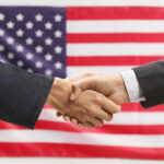 Huge Power Shift In American Business Two hands shaking in front of American flag