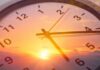Analog clock overlaid on a vibrant sunset sky