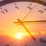 Buried Chapel Freezes Time Analog clock overlaid on a vibrant sunset sky