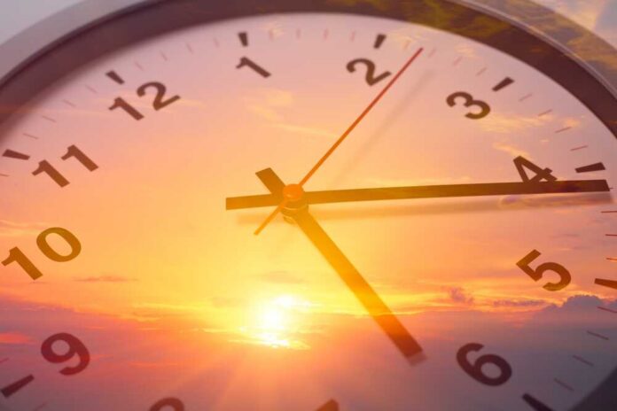 Analog clock overlaid on a vibrant sunset sky