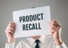 Person holding a sign reading product recall