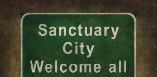 Green sign reading Sanctuary City Welcome all