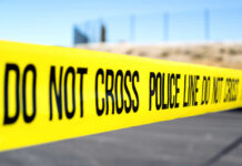 Police do not cross tape stretched across an outdoor scene