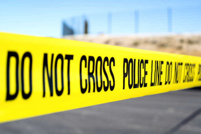 Police do not cross tape stretched across an outdoor scene