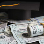 Graduation cap with rolled U.S. hundred-dollar bills