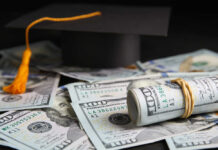 Graduation cap with rolled U.S. hundred-dollar bills