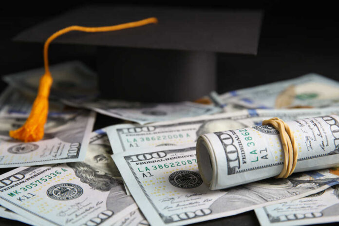 Dollar,Banknotes,And,Student,Graduation,Hat,On,Table,,Closeup.,Tuition Graduation cap with rolled U.S. hundred-dollar bills