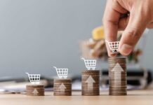 Inflation Bites, Trick-Or-Treat Roars Stacks of coins with shopping cart icons and a hand placing one on the tallest stack