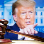 Judge’s gavel with Donald Trump pointing in the blurred background