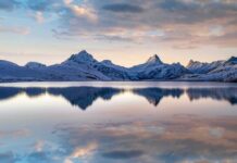 Rocky Mountain Ice Bleeds Out Snow-capped mountains reflected in a calm lake at sunrise