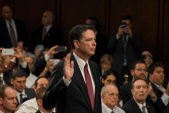 shutterstock_675303742-1 James Comey raises his right hand during a formal hearing; Jared Coreau not visible